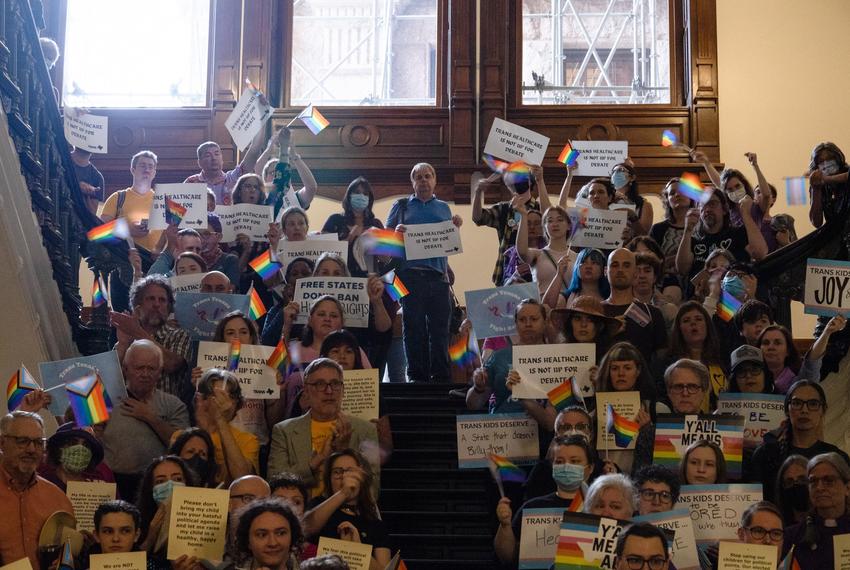 People cheer and wave rainbow flags while gathered on the stairs across from the House floor to protest against SB 14, which seeks to ban puberty blockers and hormone therapies for transgender youth, before it is heard for debate in the House at the state Capitol in Austin on May 12, 2023.