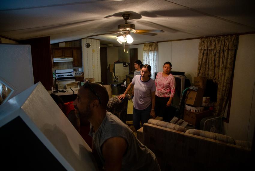 Sisters Edith, Carolina, and Maribel Velarde watch as workers from Magnolia Movers struggle to fit their fridge through the front door of their home at Congress Mobile Home Park in Austin on Aug. 29, 2022.