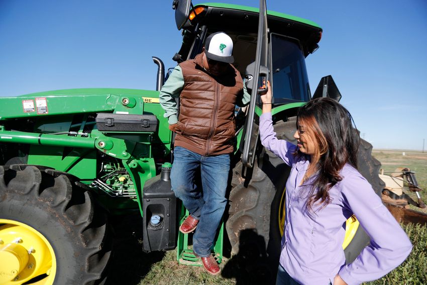 Yuleida Serrato holds the door of a new H-310 John Deere tractor for her father, Amaldo Serrato. The Serratos bought the tractor to use in their hay business. he Serrato family own and run their multigenerational family farm in and around Floydada. Amado Serrato, his wife and father came to the United States, where they and their American born kids have created a successful agricultural business.