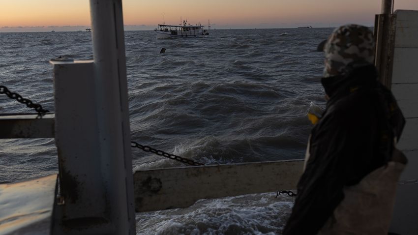 Manuel Perez watches as neighboring oyster boats maneuver around the harvesting zone in Galveston Bay, outside of Texas City, on the first day of the oyster harvesting season, on Nov. 1, 2023.
