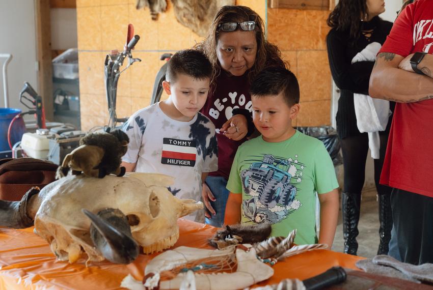 Andrea Poncho, 51, affiliated with the Alabama–Coushatta Tribe of Texas, (center) shows her sons, Waylon Poncho, 7, (left) and Gunnar Poncho, 6, (right) a display of various ways bison is utilized on Saturday, November 4, 2023 at GP Ranch in Sulphur Springs, Texas.The display was used to educate those who attended a blessing ceremony for three herds of bison gifted to Theda Pogue, affiliated with the Muscogee Creek Nation of Oklahoma, and her family on National Bison Day. One herd was recently transferred from Colorado with the help of the Tanka Fund, a Native American-led nonprofit organization and the Nature Conservancy to revitalize buffalo populations and provide resources for Native ranchers and producers.