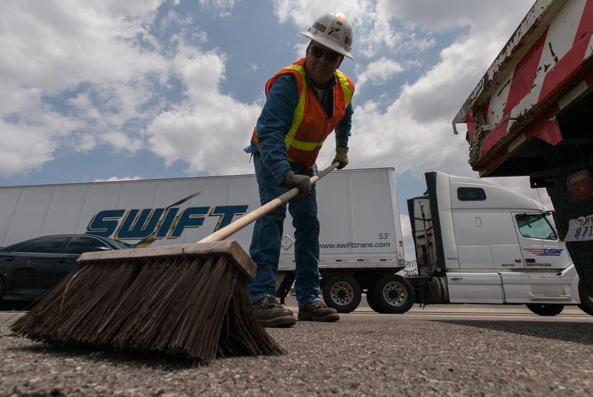 TxDOT employee Brad Shepard sweeps the road shoulder clean of the asphalt cold mix he put down while doing edge repairs on Interstate 35 in Austin on August 19th, 2013.