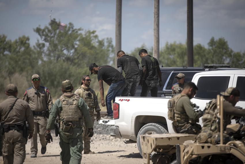 A group of migrants walk off a pick-up truck after being apprehended by Department of Public Safety officers at a train depot in Spofford on Aug. 25, 2021.