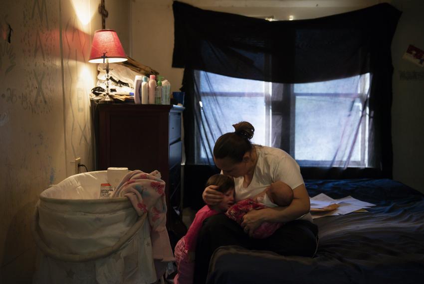 Sitting next to a pile of medical bills, Tiffany Revilla tries to calm her daughter Adillie, 1, while holding her newborn, Cheyenne, at her home in Fort Worth, Texas, Friday, Nov. 15, 2019